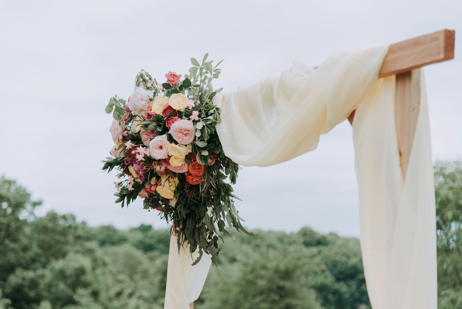 Flowers draped over a wooden ceremony arch