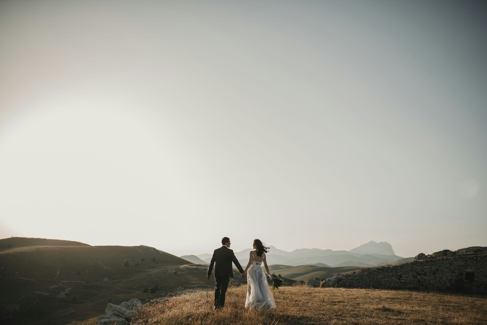 Niamh and Conor walking hand in hand through the hills at sunset